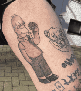 Cartoon character and wolf tattoos on arm