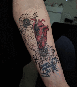 Tattoo of heart, brain, sunflowers on forearm.