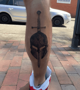 Spartan helmet and sword tattoo on leg